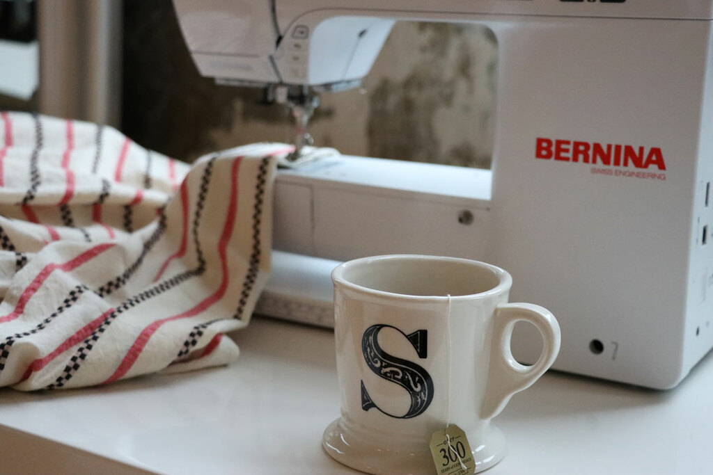 a coffee mug next to a sewing machine