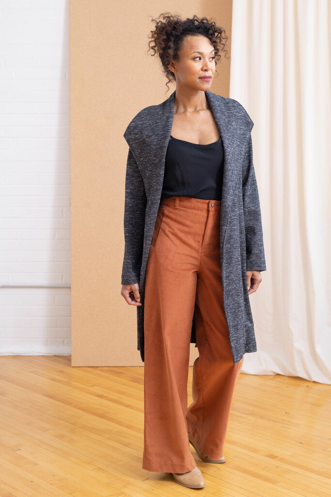 A model wearing a black camisole, gray sweater jacket, and rust colored wide legged trousers.