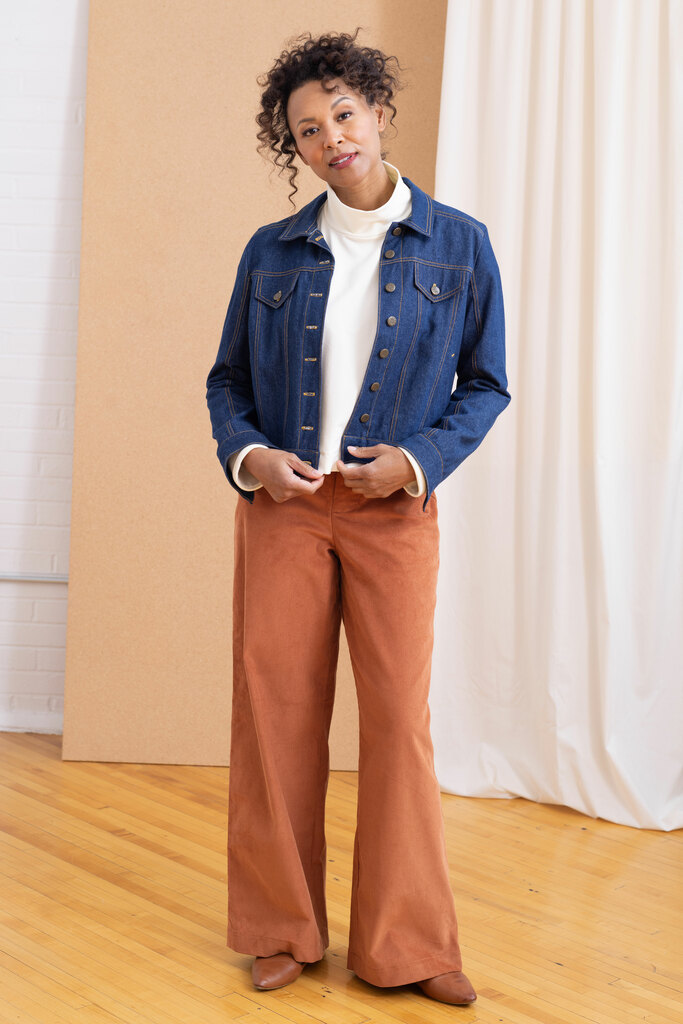 A model wearing a white pullover sweater, denim jacket, and wide legged trousers. All are Seamwork sewing patterns